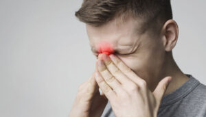 Man holding nose in pain.